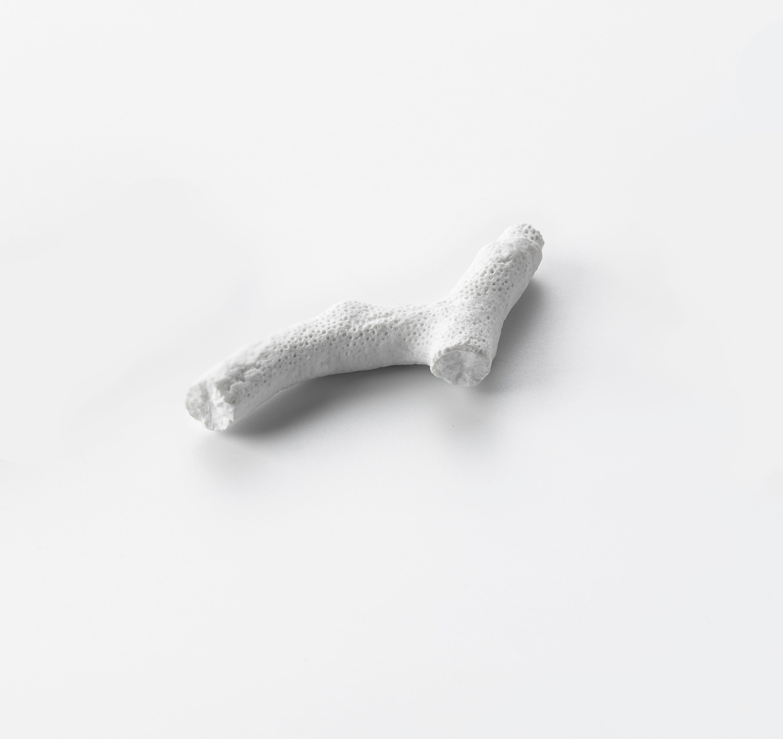 Coral cutlery rest in porcelain, ocean-inspired luxury tableware, elegant utensil holder for refined dining settings.